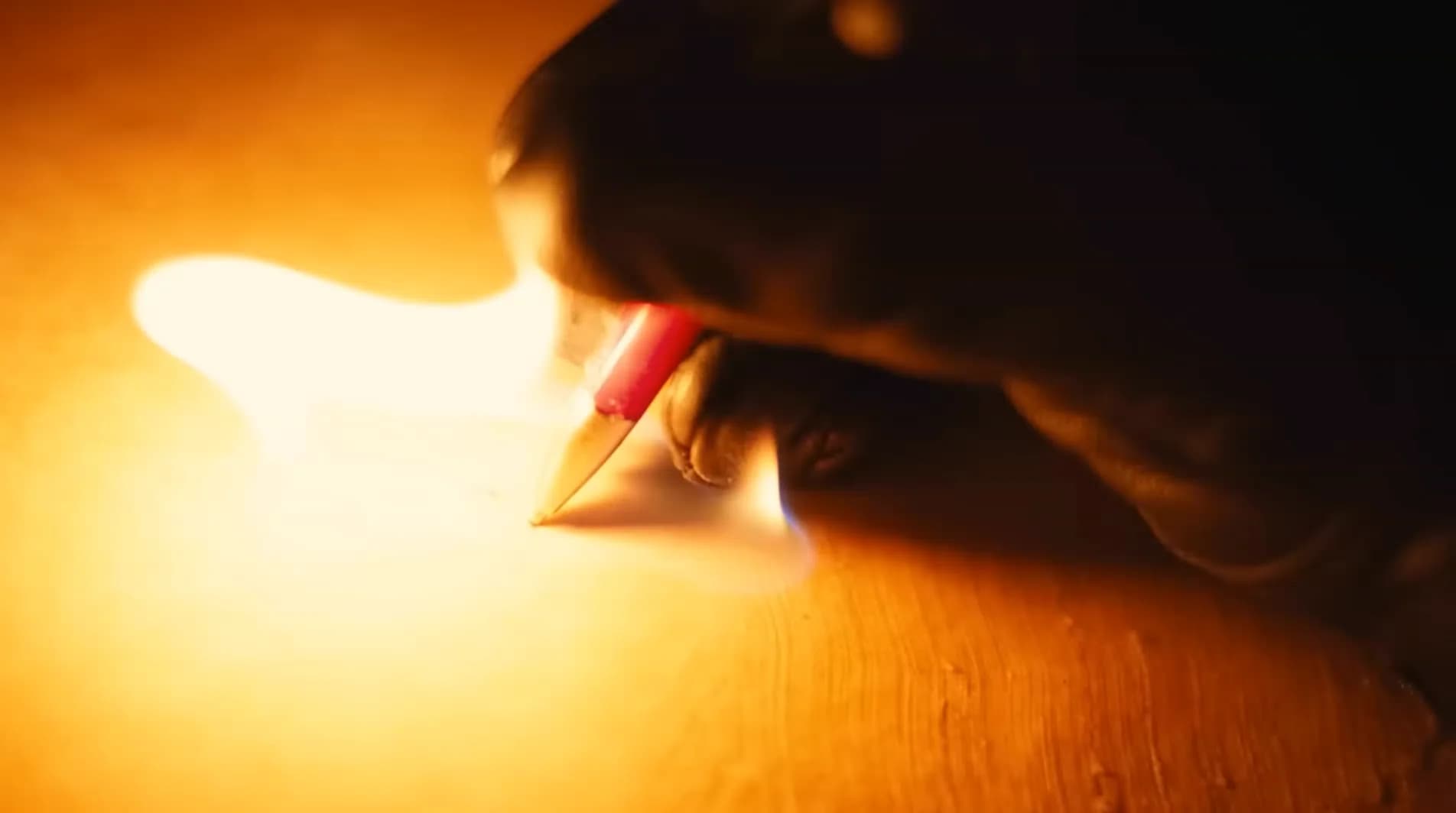 A hand writing beside a flame